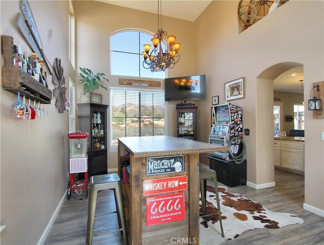 kitchen with a towering ceiling, decorative light fixtures, dark hardwood / wood-style floors, tile countertops, and a notable chandelier