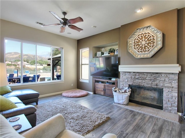 living room with a mountain view, wood-type flooring, a healthy amount of sunlight, and a fireplace