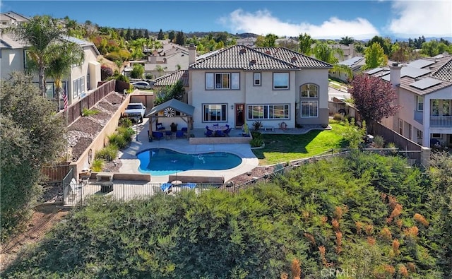 rear view of property featuring a patio area and a fenced in pool