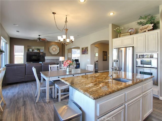 kitchen featuring pendant lighting, sink, a kitchen island with sink, appliances with stainless steel finishes, and white cabinets