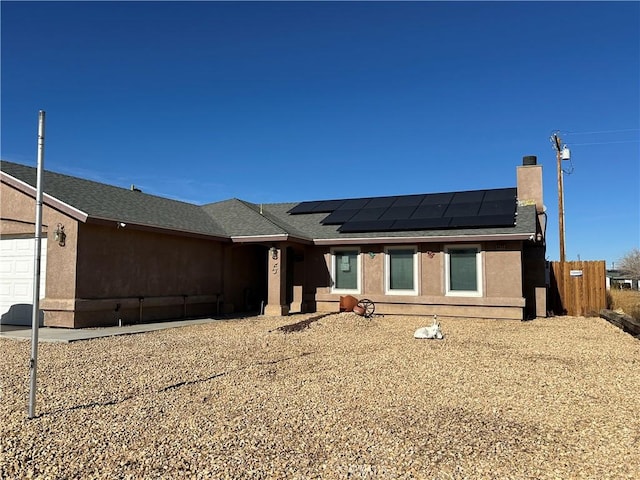 ranch-style house featuring a garage and solar panels