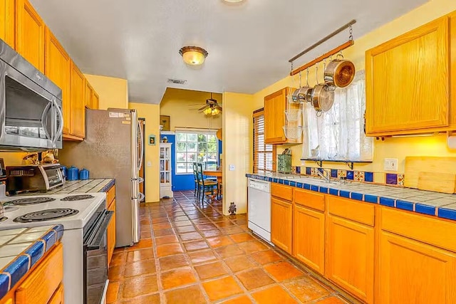 kitchen with white appliances, tile counters, sink, ceiling fan, and light tile patterned floors