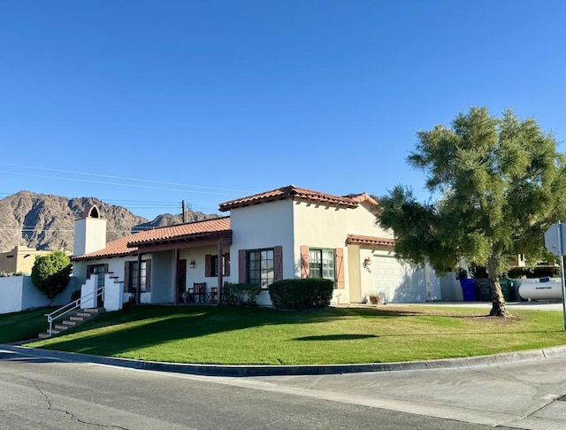 view of front of property featuring a garage, a front lawn, and a mountain view