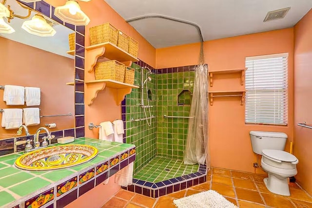 bathroom with toilet, tile patterned floors, walk in shower, and sink