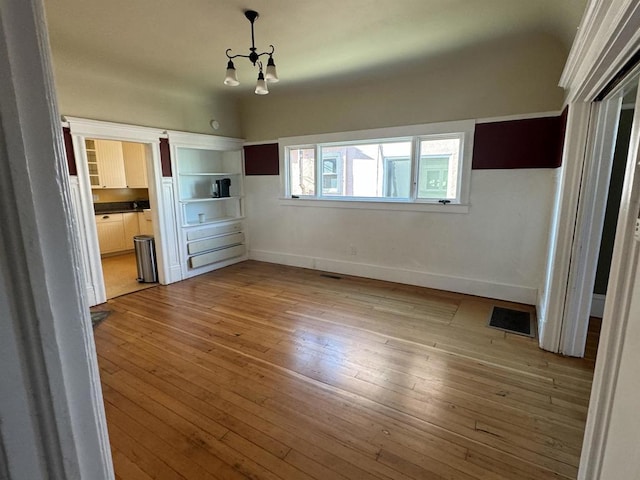 unfurnished bedroom featuring light hardwood / wood-style floors and an inviting chandelier