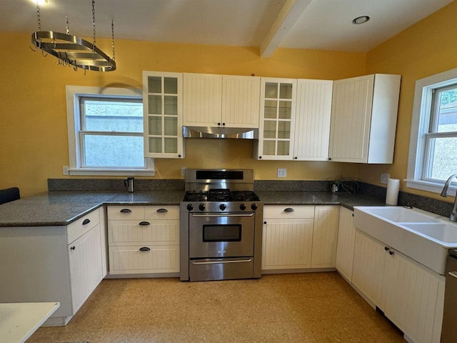 kitchen with sink, white cabinets, stainless steel range with gas stovetop, and beamed ceiling