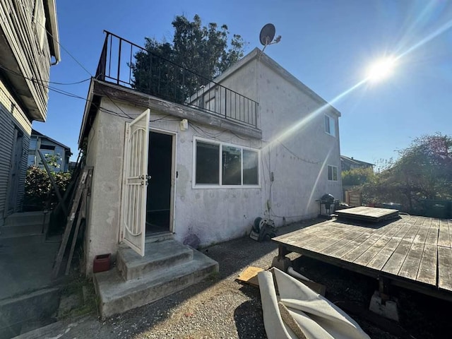 back of house featuring a balcony and a deck