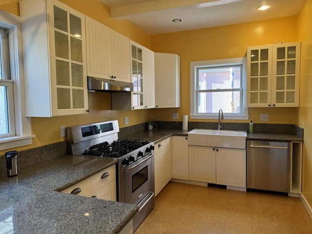 kitchen with stainless steel appliances, dark stone countertops, beam ceiling, and sink