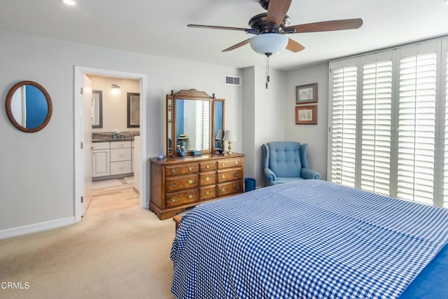 bedroom with ceiling fan, light colored carpet, and ensuite bathroom