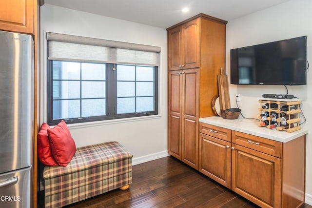 kitchen featuring light stone countertops, dark wood-type flooring, and stainless steel refrigerator