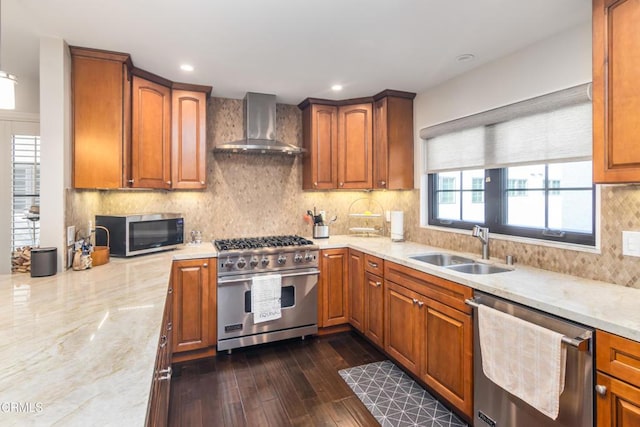 kitchen with light stone countertops, wall chimney exhaust hood, stainless steel appliances, sink, and dark hardwood / wood-style floors