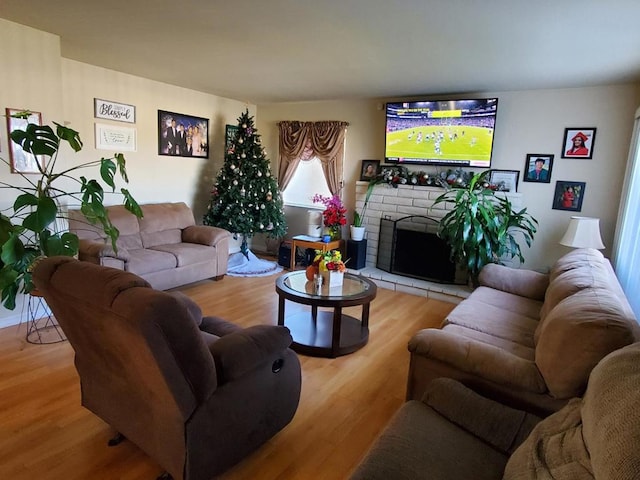 living room featuring a brick fireplace and light wood-type flooring