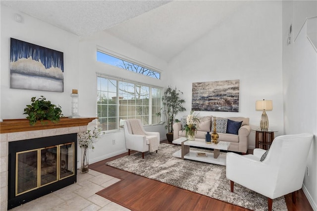 living room with vaulted ceiling, a tile fireplace, and a textured ceiling