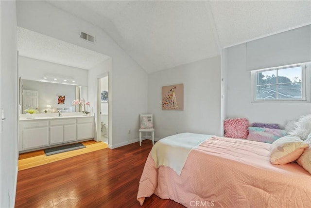 bedroom featuring ensuite bathroom, vaulted ceiling, sink, and hardwood / wood-style floors