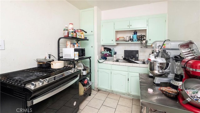 kitchen with decorative backsplash, light tile patterned floors, tile counters, and gas range oven