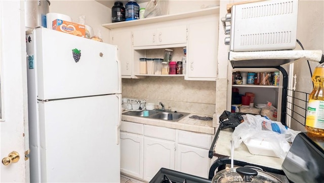 kitchen with backsplash, tile countertops, sink, white cabinetry, and white refrigerator