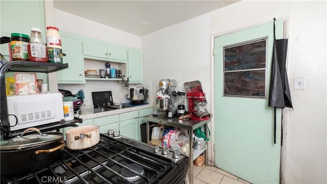 kitchen featuring light tile patterned floors, tile counters, and gas stove