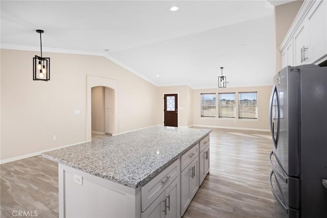 kitchen featuring ornamental molding, lofted ceiling, stainless steel fridge, and hanging light fixtures