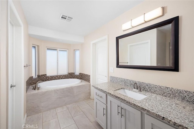 bathroom featuring vanity, tile patterned floors, and a relaxing tiled tub