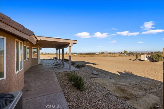 view of yard featuring a rural view, a patio area, and central AC