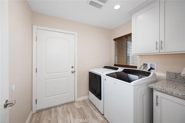 laundry room featuring light wood-type flooring, cabinets, and washing machine and dryer