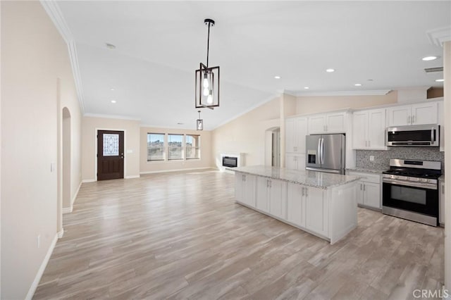 kitchen with white cabinets, a center island, lofted ceiling, stainless steel appliances, and backsplash