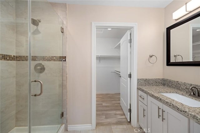 bathroom featuring a shower with shower door and vanity