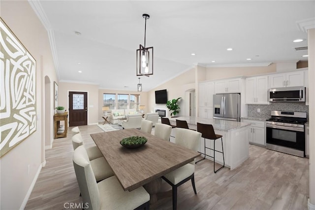 dining room featuring vaulted ceiling, ornamental molding, and light wood-type flooring