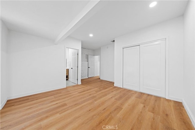 interior space with a closet, beamed ceiling, and light hardwood / wood-style flooring