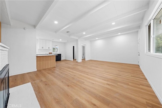 unfurnished living room featuring a wealth of natural light, beam ceiling, and light wood-type flooring