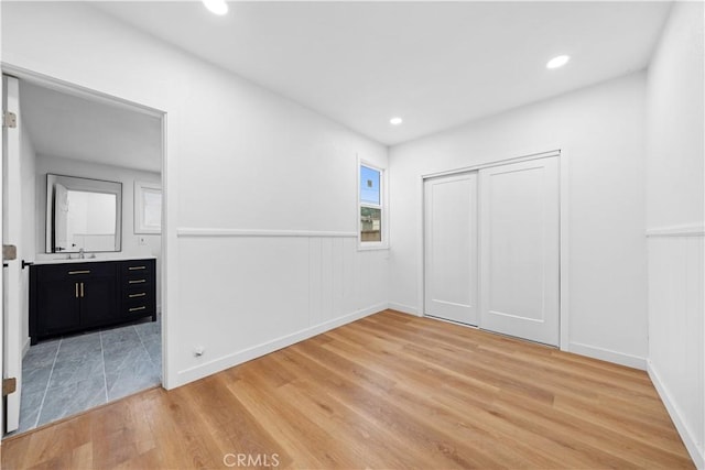 unfurnished bedroom with wood-type flooring, sink, and a closet