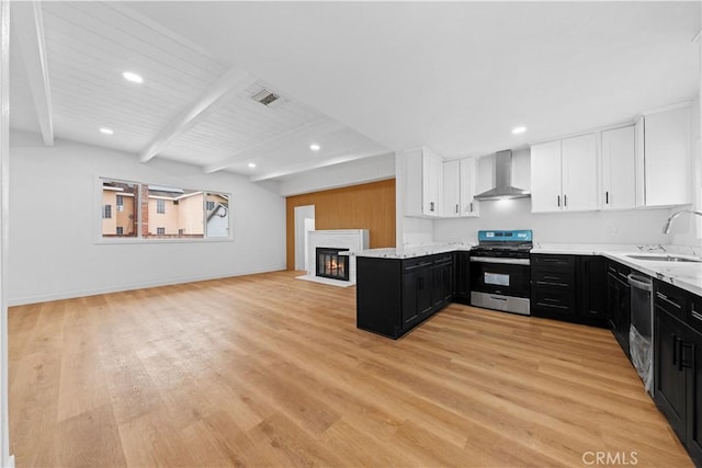 kitchen with white cabinetry, appliances with stainless steel finishes, wall chimney range hood, beam ceiling, and sink