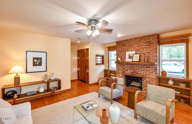 living room with a brick fireplace, light hardwood / wood-style flooring, plenty of natural light, and ceiling fan