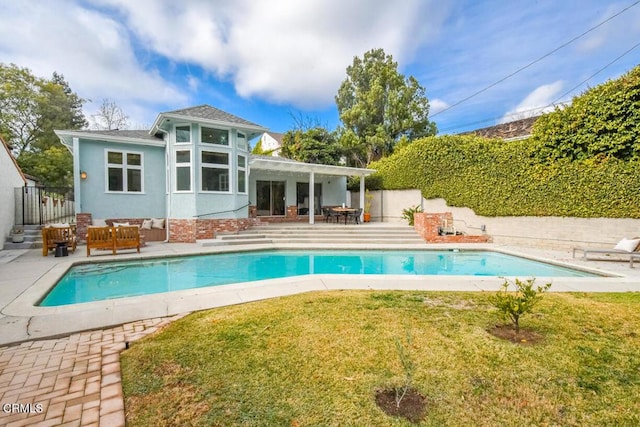 back of property featuring a fenced in pool, a yard, an outdoor hangout area, and a patio