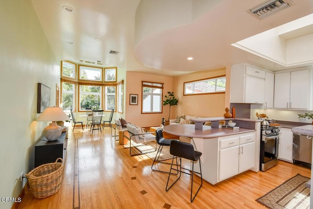 kitchen with a breakfast bar, kitchen peninsula, white cabinetry, and stainless steel stove