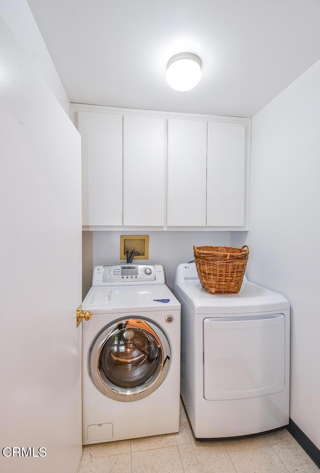 clothes washing area with washer and dryer and cabinets