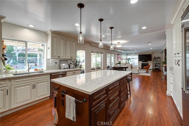 kitchen featuring decorative light fixtures, dark hardwood / wood-style flooring, stainless steel dishwasher, light stone counters, and sink