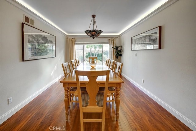 dining space with dark hardwood / wood-style flooring and crown molding