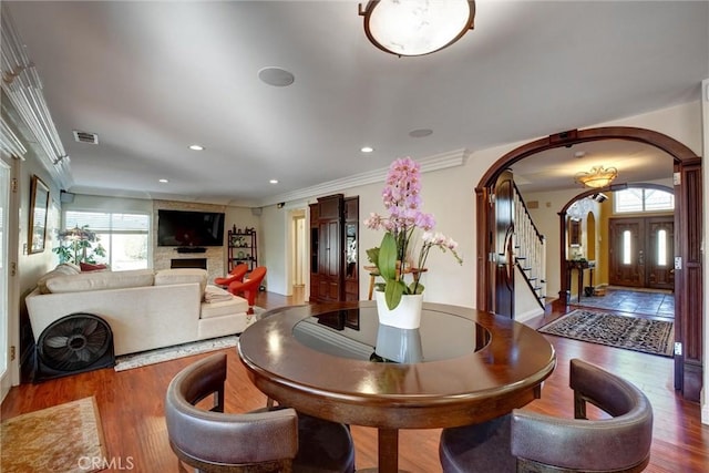 dining room with hardwood / wood-style flooring, ornamental molding, and a fireplace