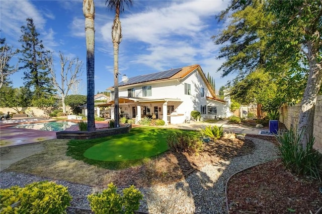 rear view of house featuring solar panels and a patio