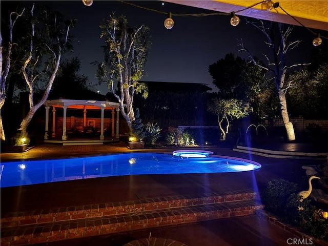 pool at twilight featuring an in ground hot tub