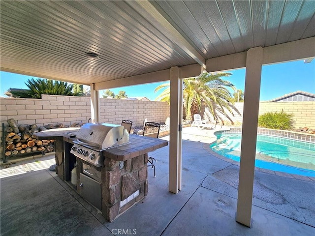 view of patio with a fenced in pool, a grill, and exterior kitchen