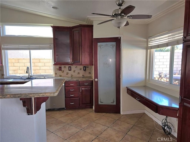 kitchen featuring light tile patterned flooring, a breakfast bar, dishwasher, backsplash, and crown molding