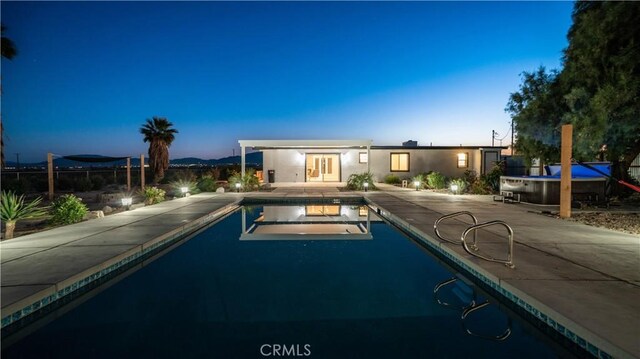 pool at dusk featuring a patio