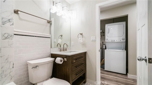 bathroom with vanity, tile walls, toilet, stacked washing maching and dryer, and hardwood / wood-style flooring