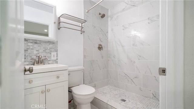 bathroom featuring toilet, tiled shower, tasteful backsplash, and vanity