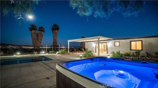 pool at twilight featuring a hot tub and a patio