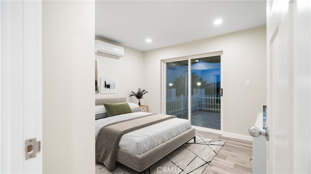 bedroom featuring access to outside, light hardwood / wood-style flooring, and a wall mounted air conditioner