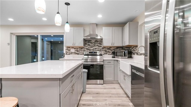 kitchen featuring stainless steel appliances, decorative backsplash, wall chimney range hood, pendant lighting, and a center island