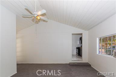 spare room featuring ceiling fan, lofted ceiling, and dark colored carpet